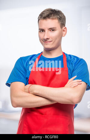 Happy Portrait von einem Mann in einem roten Schürze auf grauem Hintergrund Stockfoto
