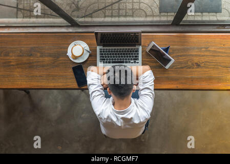 Der Mann neben Laptops, Smartphones und Tablet in der Cafeteria schlafen Stockfoto