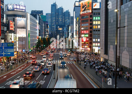 Menschenmassen entlang einer befahrenen Straße vor dem Bahnhof Shinjuku in Tokio Stockfoto