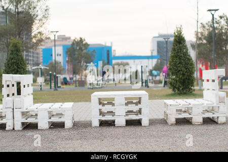 Holzbank aus Paletten der Fracht cargo Fällen zum Sitzen. Kreative Café im Freien Tisch und Bänken. Park im Hintergrund. Stockfoto