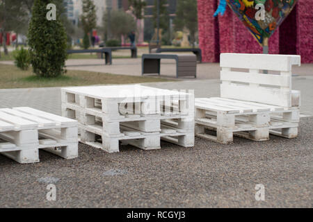 Holzbank aus Paletten der Fracht cargo Fällen zum Sitzen. Kreative Café im Freien Tisch und Bänken. Park im Hintergrund. Stockfoto