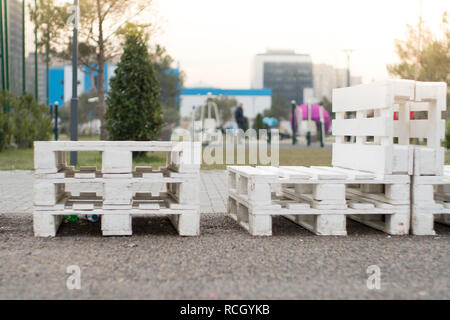 Holzbank aus Paletten der Fracht cargo Fällen zum Sitzen. Kreative Café im Freien Tisch und Bänken. Park im Hintergrund. Stockfoto