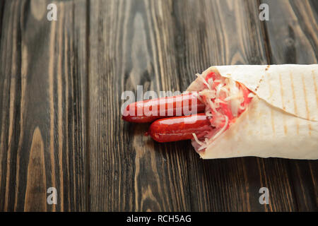 Hausgemachte Wurst in pita Brot auf hölzernen Hintergrund. Foto mit Stockfoto