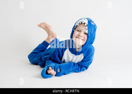 Fröhliche kleine Junge auf einem weißen Hintergrund im Schlafanzug Posing, blauhai Kostüm Stockfoto