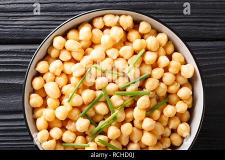 Bio snack gekochte Kichererbsen close-up in einem schwarzen Schüssel auf einen hölzernen Tisch. horizontal oben Ansicht von oben Stockfoto