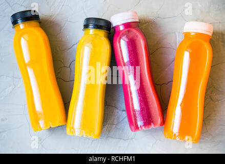 Rot, orange und Gelb Saft, frische Smoothies Flaschen auf konkreten Hintergrund, gesunden Lebensstil Konzept, Ansicht von oben, gesunden Lebensstil Konzept Stockfoto