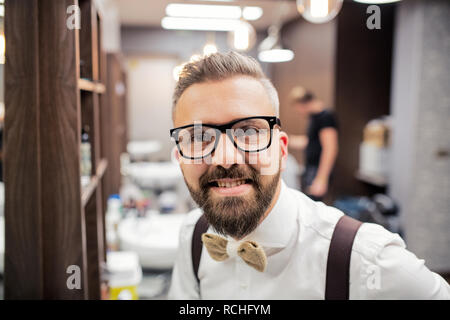 Ein Porträt von Stattlichen hipster Mann Client stehen in Friseur. Stockfoto
