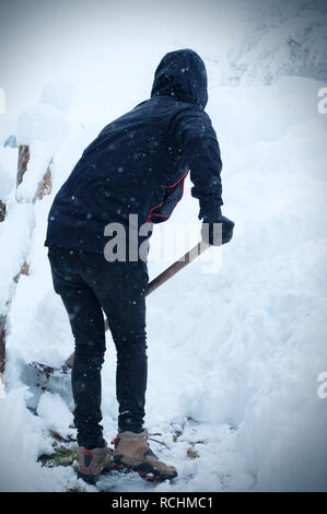 Mann mit Schneeschaufel reinigt die Bürgersteige im Winter. Winter. Zyklon in Europa Stockfoto