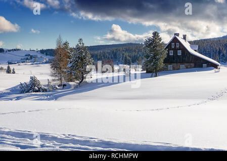 Winter Berglandschaft in sonniger Tag. Dunkle Wolken am blauen Himmel. Siedlung Jizerka in Isergebirge im Winter, Tschechische Republik. Siedlung Jizerka Stockfoto