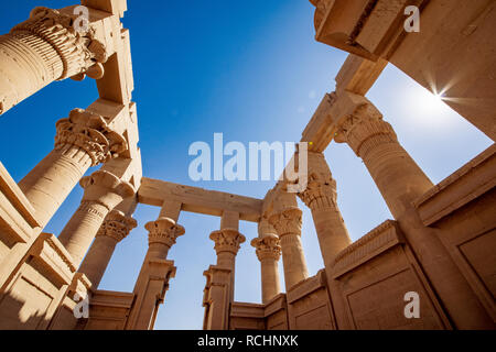 Trajan Kiosk im Philae Innenansicht. Säulen geschmückt mit hyeroglyphs. Lens flare Effekt von der Sonne. Stockfoto