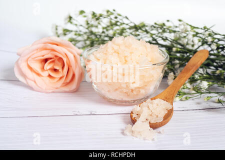 Natürliche Hautpflege Konzept. Organische Kosmetik mit rosa Salz Spa in Glas und Holz Schüssel Löffel dekorieren mit rosa und weiße Blume Stockfoto