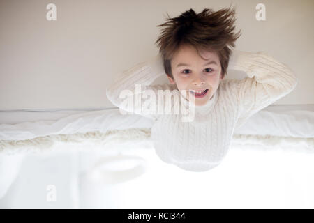 Cute Portrait von Kind auf den Kopf, und er liegt auf dem Bett und lächelt in die Kamera und das Spielen mit Spielzeug Stockfoto