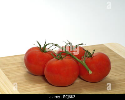 Tomaten, Strauch Tomaten mit Stängel, groß, auf einem Holzbrett vor einem weißen Hintergrund Stockfoto