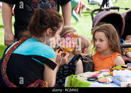 Artist mit jungen Mädchen in ihr Gesicht gemalt, während ihr Freund sieht bei der Gala in Rhu, Argyll, Schottland Stockfoto