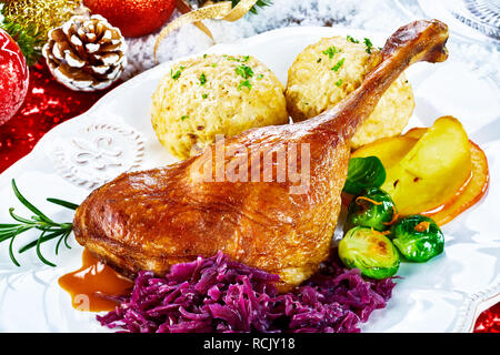 Knusprige golden gebratene Weihnachten Türkei Bein mit frischem Gemüse und Knödel serviert auf einem Tisch mit Weihnachten Dekorationen in der Nähe zu sehen, einstellen Stockfoto