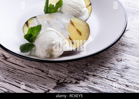 Gegrillte mango Nachtisch mit Eis serviert mit Minze auf hellgrau Platte, köstliche behandeln, Nahaufnahme, selektiven Fokus Stockfoto