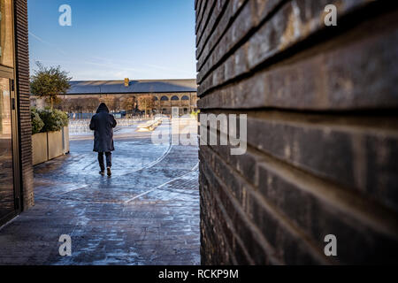 Hooded Abbildung zu Fuß durch, Getreidespeicher Square, Kings Cross, London, UK. Stockfoto