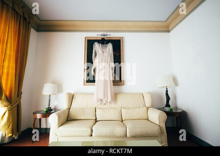 Kleid der Braut hängt vor dem Hintergrund der Bild im Zimmer Stockfoto