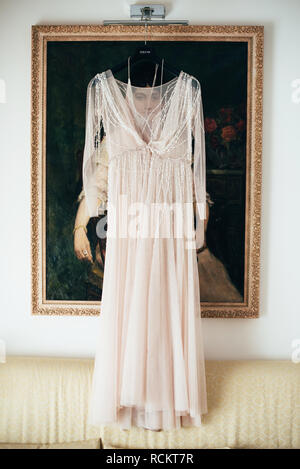 Kleid der Braut hängt vor dem Hintergrund der Bild im Zimmer Stockfoto