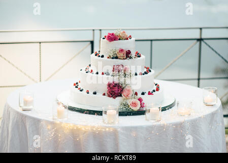 Eine wunderschöne Hochzeit Kuchen in vier Stufen wird auf dem Tisch vor dem Hintergrund der malerischen See Stockfoto
