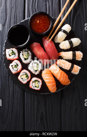 Japanisches Sushi essen. Maki ands Brötchen mit Thunfisch, Lachs, Garnelen, Krabben und Avocado mit zwei Saucen close-up auf einer Schiefertafel Platte. Vertikal oben Blick von Abo Stockfoto