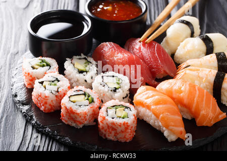 Satz frischer Maki, Uramaki und Nigiri Sushi, auf schwarze Platte in der Nähe serviert. Horizontale Stockfoto