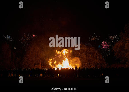 Eine Masse von Leuten, die gerade ein osterfeuer mit Feuerwerk am Himmel über Stockfoto