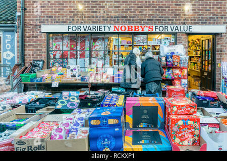 Zwei Käufer suchen Artikel zum Verkauf auf Tischen draußen Nobby's General shop in Wells-next-the-Sea, Norfolk. Stockfoto