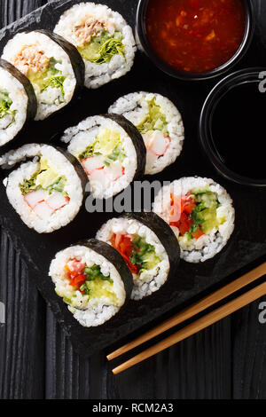 Einstellen der japanischen Rollen futomaki mit Soja und Chili Saucen close-up auf einer Schiefertafel Board auf dem Tisch. Vertikal oben Ansicht von oben Stockfoto