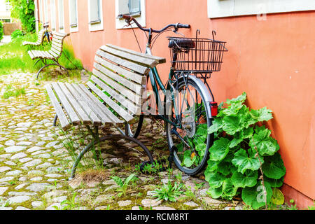 Altes Fahrrad mit Korb lehnte sich gegen eine Hauswand Stockfoto