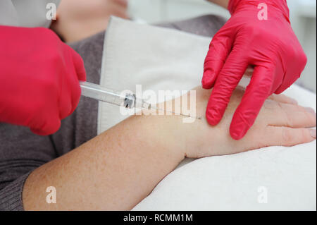 Arzt cosmetologist Dermatologe führt eine Sitzung der Mesotherapie oder biorevitalization - Entfernung von Pigmentflecken auf der alten Frauen die Hände. Stockfoto