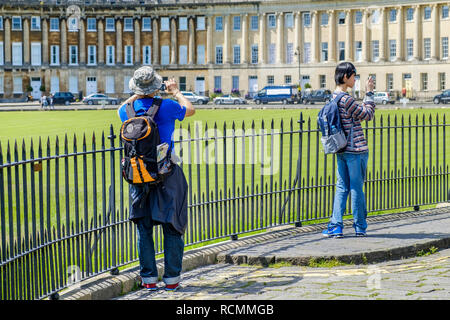 Zwei Männer/Touristen abgebildet sind ein Foto der Royal Crescent eine der kultigsten Sehenswürdigkeiten Bad in der Badewanne, Somerset England Großbritannien Stockfoto