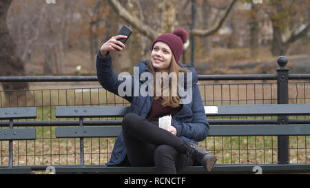 Junge Frau sitzt auf einer Bank im Central Park in New York Stockfoto