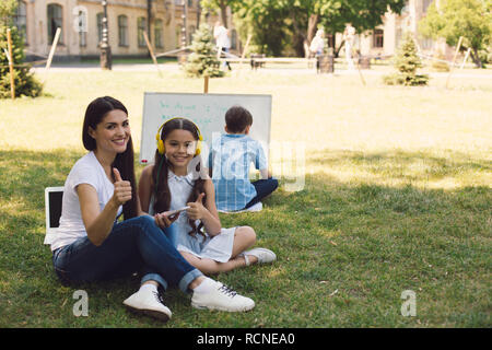 Kinder und Lehrer genießen in Park Stockfoto