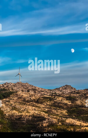 Anzeigen einer Windkraftanlage auf Berge, dramatischer Sonnenuntergang Himmel mit Mond im Hintergrund, in Portugal... Stockfoto