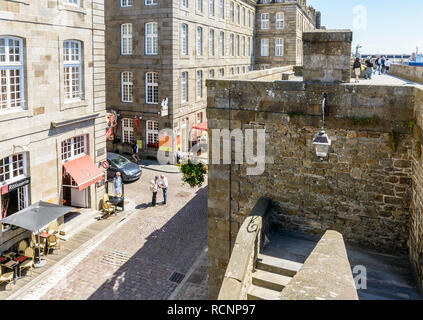 Blick über die Dinan Tor in der Altstadt von Saint-Malo in der Bretagne, Frankreich, mit Leute saßen auf der Terrasse eines Cafés oder bei einem Spaziergang auf der Stadtmauer. Stockfoto