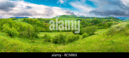 Wunderschöne Landschaft Panorama im Frühling. grasbewachsenen Hügeln und Wiesen. Bäume mit Laub an Hängen. Berggipfel in der Ferne. Stockfoto