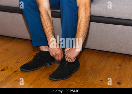 Ein zukünftiger Ehemann verschärft für eine Hochzeit, indem Sie auf seine Schuhe und seine Krawatten binden. 2019 Stockfoto