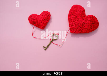 Bronze Skeleton Key und Rosa gestrickt, Herzen, antike, rustikale Tasten auf rosa Hintergrund. Happy Valentine's Day card. Symbol der Liebe. Hobby Konzept. heartbeat, Gefühle, Romantik Konzept. Platz kopieren. Stockfoto
