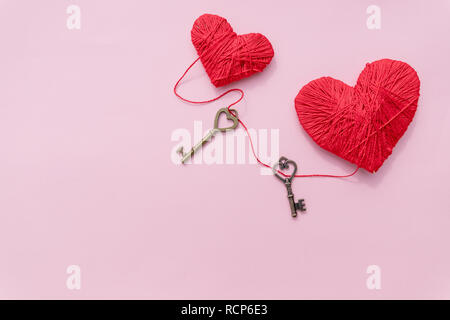 Bronze Skeleton Key und Rosa gestrickt, Herzen, antike, rustikale Tasten auf rosa Hintergrund. Happy Valentine's Day card. Symbol der Liebe. Hobby Konzept. heartbeat, Gefühle, Romantik Konzept. Platz kopieren. Stockfoto