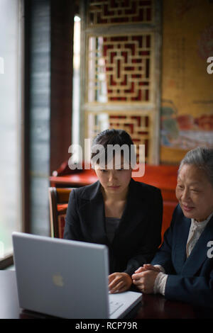Ältere Frau und junge Frau mit einem Laptop zusammen an einer chinesischen Cafe. Stockfoto