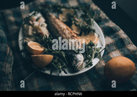 Gegrillter Fisch auf dem Teller mit Zitrone und Salat serviert. Stockfoto