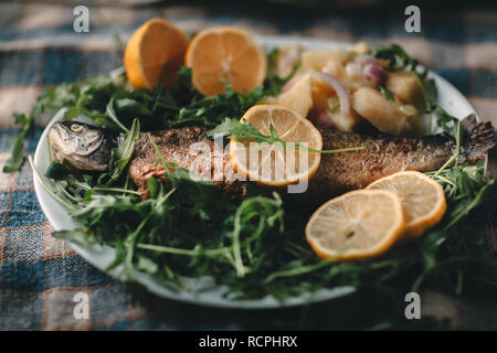 Gegrillter Fisch auf dem Teller mit Zitrone und Salat serviert. Stockfoto