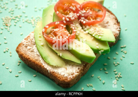 Leckere Toasts mit Avocado, Tomaten in Scheiben geschnitten und gehören insbesondere Samen auf blauem Hintergrund mit Copyspace. Gesunde Ernährung Konzept. Stockfoto