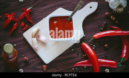 Hausgemachte heiße Soße in einer weißen Schüssel auf einem hölzernen Hintergrund Stockfoto