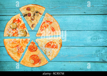 Scheiben Pizza mit verschiedenen Füllungen auf einem blauen Hintergrund aus Holz. Alte Karten. Stockfoto