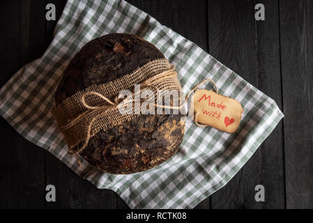 Selbstgebackenes Brot auf ein grünes Handtuch für die Küche. Flach Bild mit einem rustikalen Holztisch Stockfoto