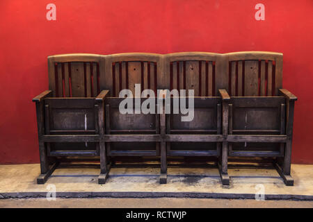 Traditionelle Thai asiatische Vintage Retro Holz- strukturierte Stühle auf rote Wand Hintergrund. Rustikale Architektur Home Interior, Haus Möbel Dekoration des Stockfoto