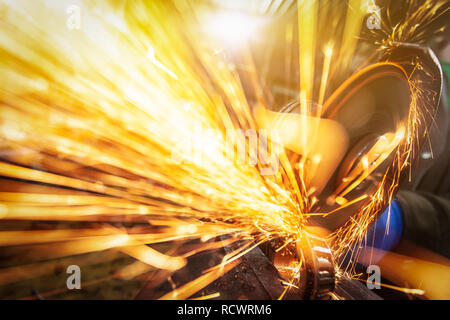Eine Nahaufnahme von einem Automechaniker mit einem Metall Grinder Lager in einer Werkstatt zu schneiden, helle Blitze fliegen in verschiedene Richtungen. Die Arbeit der Aut. Stockfoto