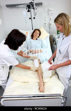 Krankenschwestern die Behandlung eines Patienten in einem Krankenhausbett ändern Stockfoto